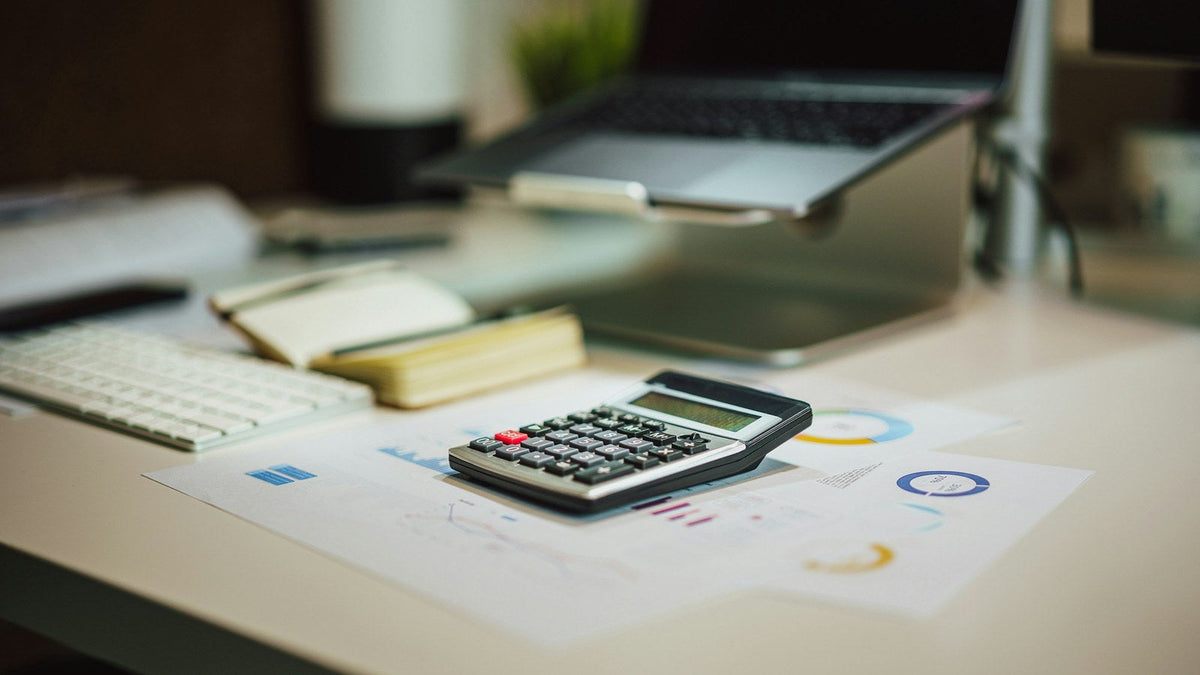 Calculator beside a laptop on a working desk