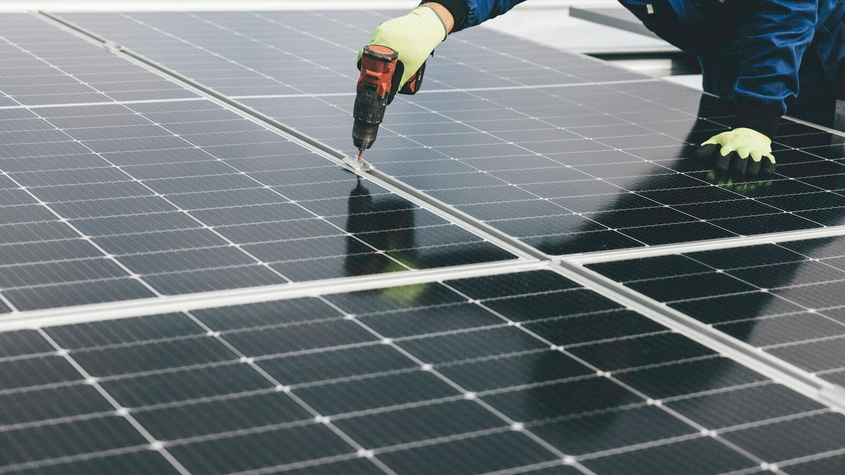 Technician installing solar panels on a commercial roof