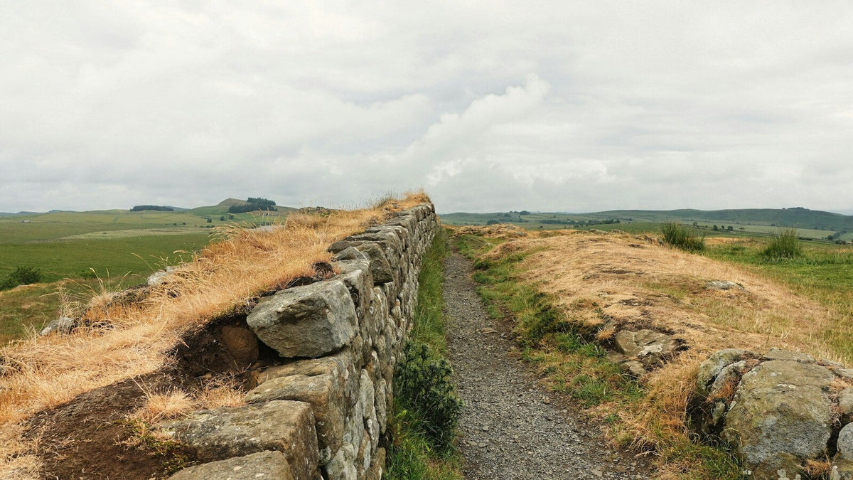A dry-stone wall crossing open British countryside beneath an overcast sky.